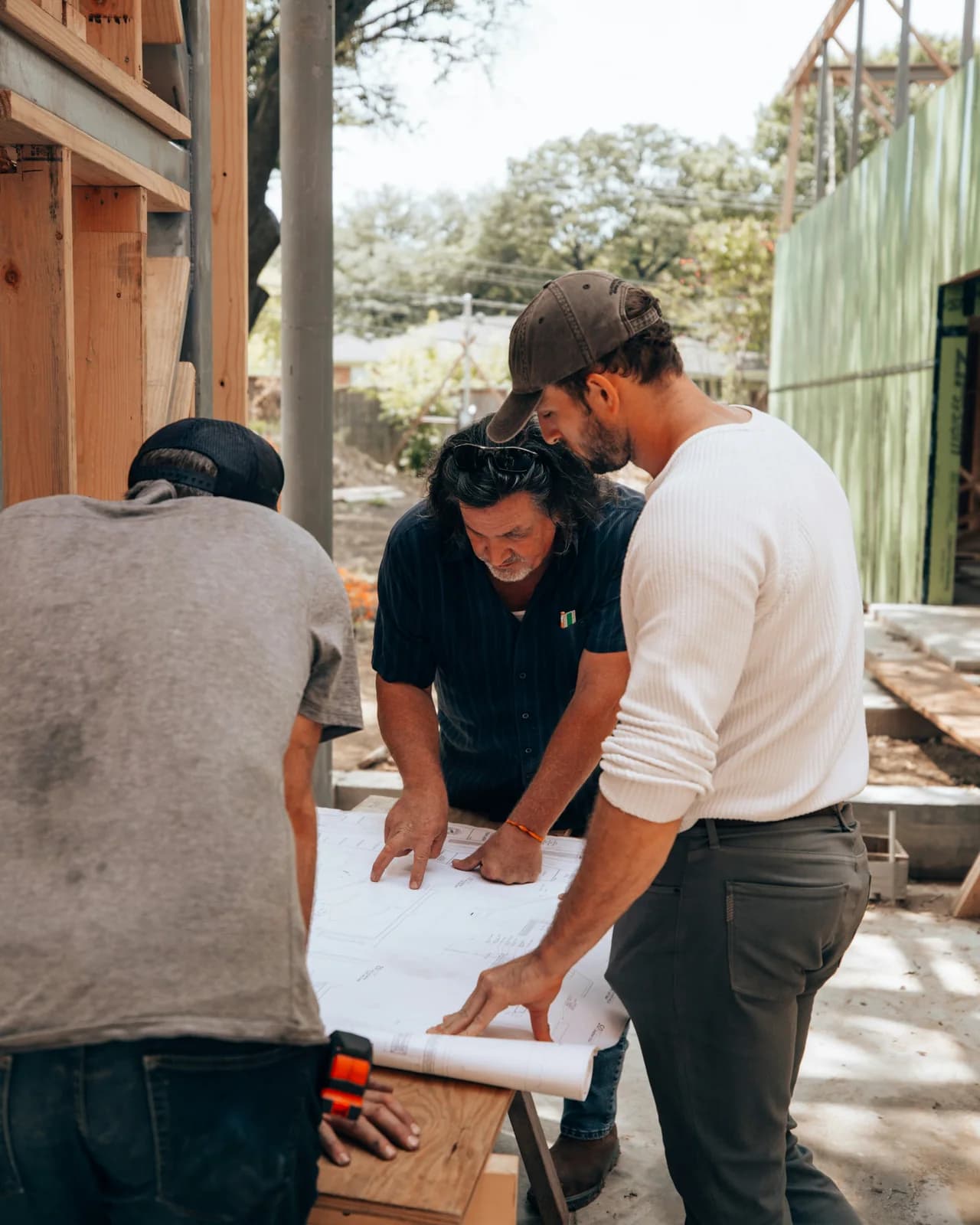 Three people reviewing plans together on a jobsite.