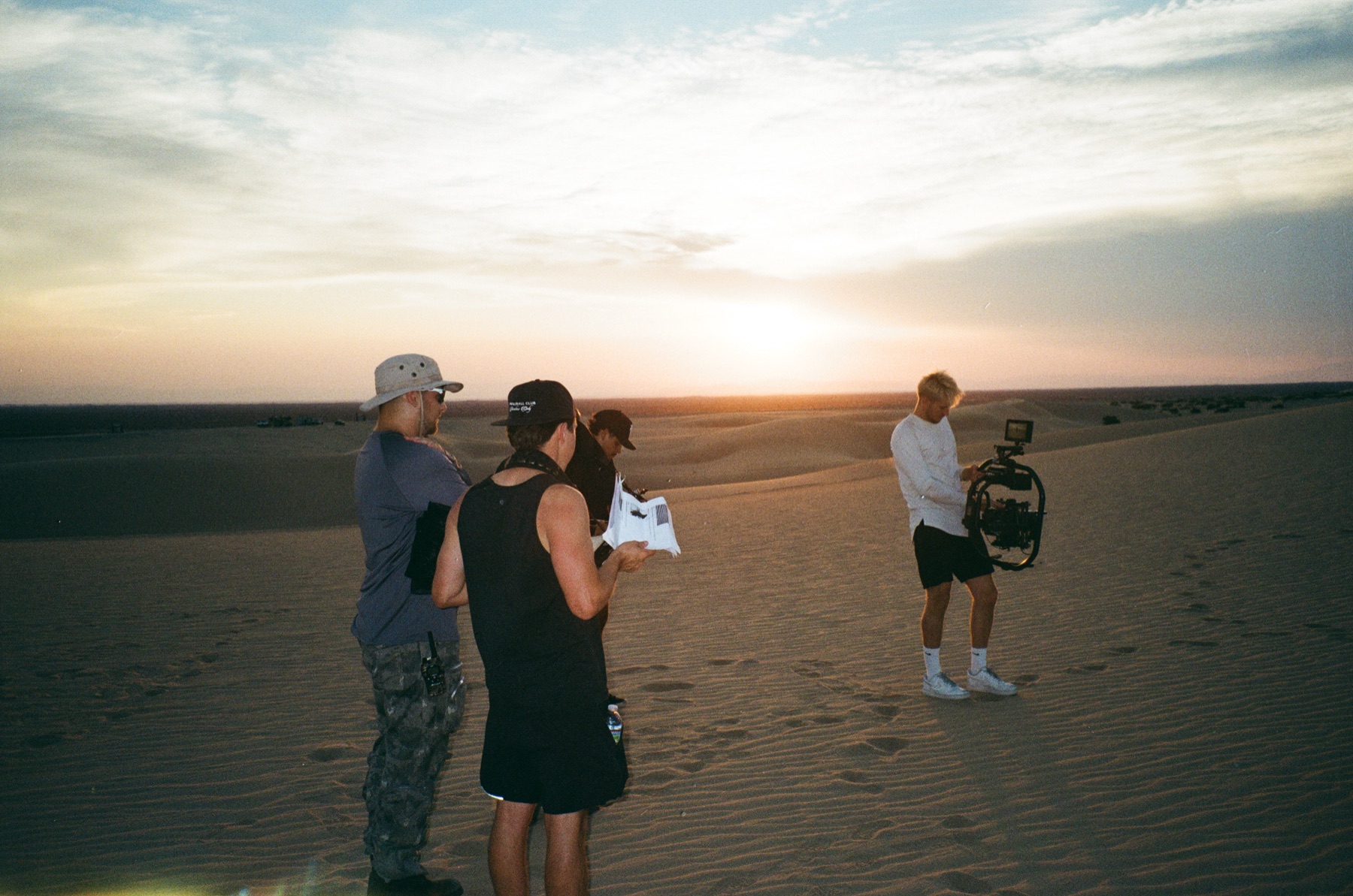 Crew reviewing a shot at golden hour on a desert dune
