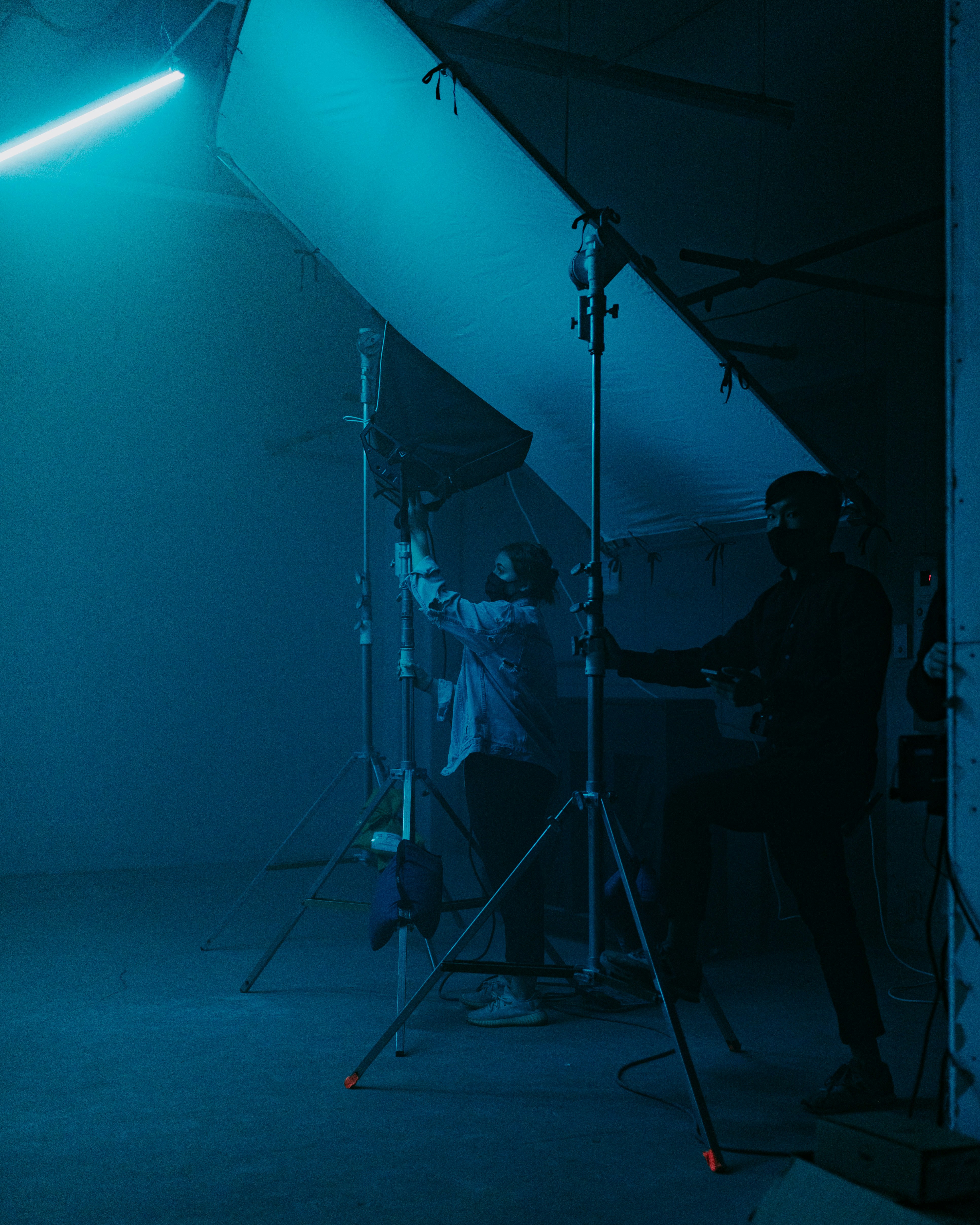 Crew adjusting an overhead silk, teal practical light.